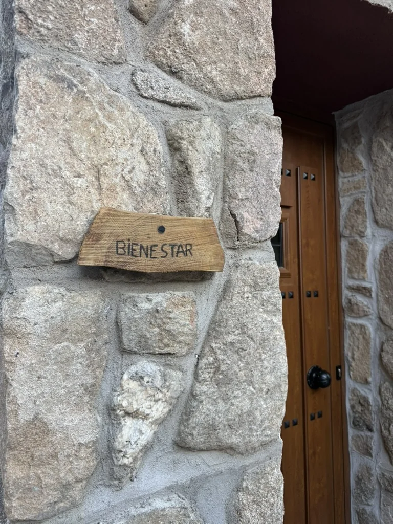 Cartel de madera con la palabra Bienestar sobre el muro de piedra de Monte Bebiome