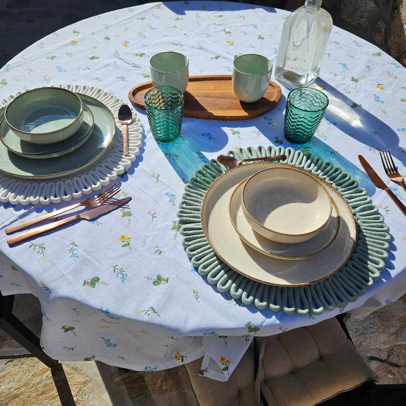 Mesa preparada para el desayuno en el patio de Monte Bebiome, con vajilla de cerámica y mantel de flores